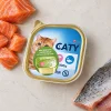Flat-lay 200064b CATY Losos & pstruh paštika 100 g se syrovým lososem a pstruhem na světlé kuchyňské lince.