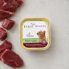 Flat-lay 20001 FIRST CLASS Zvěřinová paštika 100 g se syrovou zvěřinou na světlé kuchyňské lince. Label ref = BaseLinker packshot 620 px.