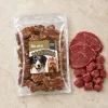 Flat-lay Masíčka 204901 (režim Produkt + suroviny): plný 300g sáček dle e-shop packshotu b64f08ae, syrové hovězí asymetricky, travertin, evergreen. Reference surovin AI-generovaná (HF job 8e2a8f68, 2,75 cr).