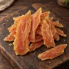 Solo surovina Akinu MASÍČKA Kuřecí stripsy 300 g (204864) — pamlsek psi/kočky, hromádka na tmavém prkénku.
