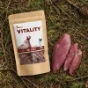 Flat-lay Bažant jerky 176169 – sáček + syrové bažantí maso na lesním jehličí.