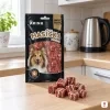 Sáček Kachní měkké kostky stojí na kuchyňské lince, vepředu hrstka kostek, ranní světlo