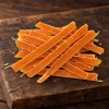 Solo surovina Akinu Masíčka Premium Losos s treskou mini proužky pro kočky 50 g (282056) — hromádka mini proužků na rustikálním tmavém prkénku, teplé světlo. Kategorie pamlsek_psi_kocky, varianta p1 ze 4.